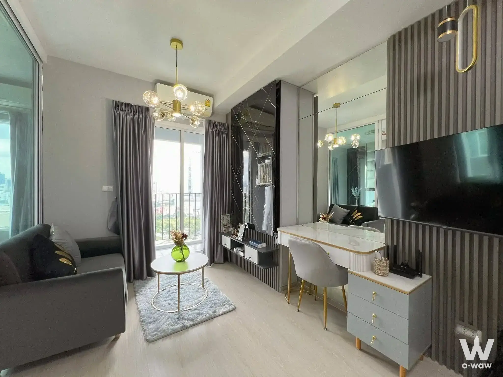 Modern living room and study area with blue rug, gold accents, and balcony view in 1-bed rental at Chapter One Eco