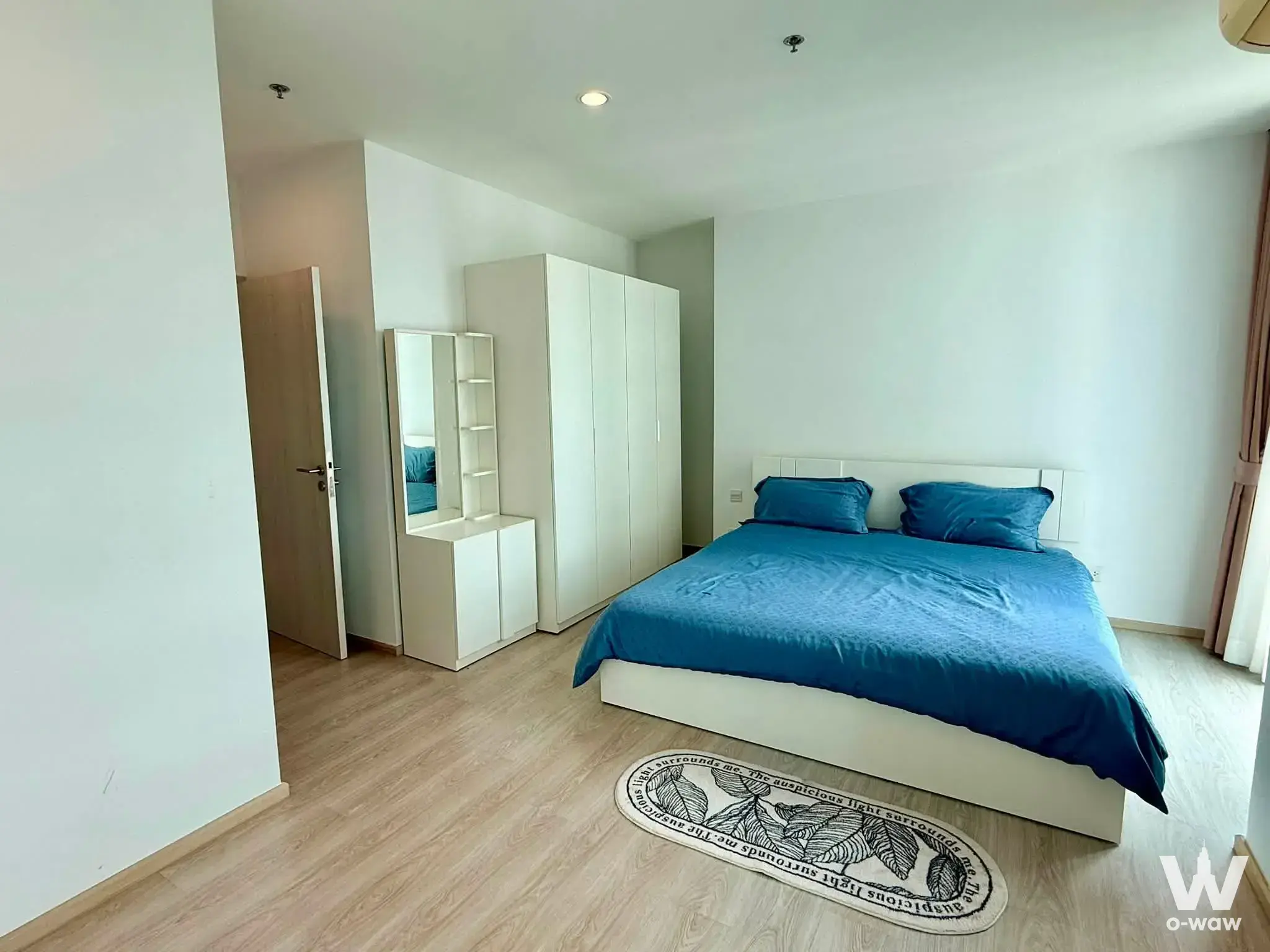 Bright bedroom with white walls, wood floors, and blue linens in 2-bed condo for rent at Noble Revolve Ratchada 2