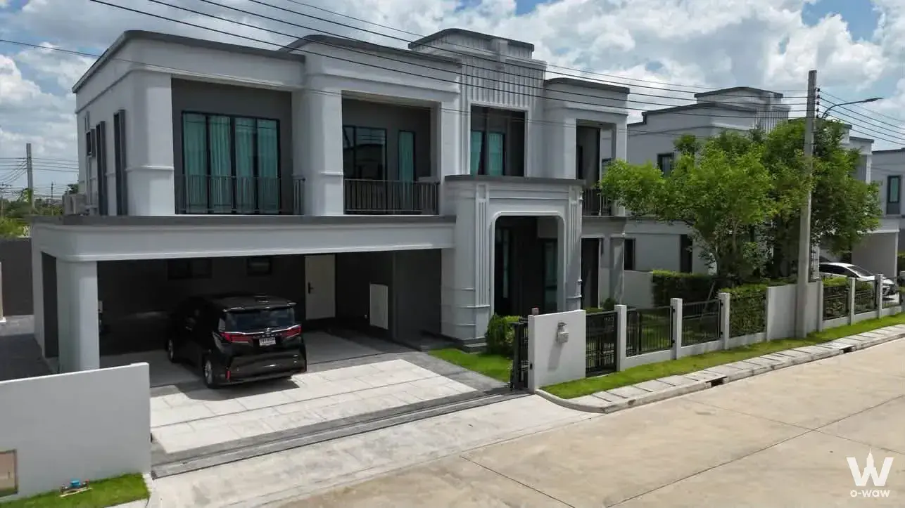 Modern two-story townhouse exterior with grey stucco facade, open-air carport, and manicured lawn