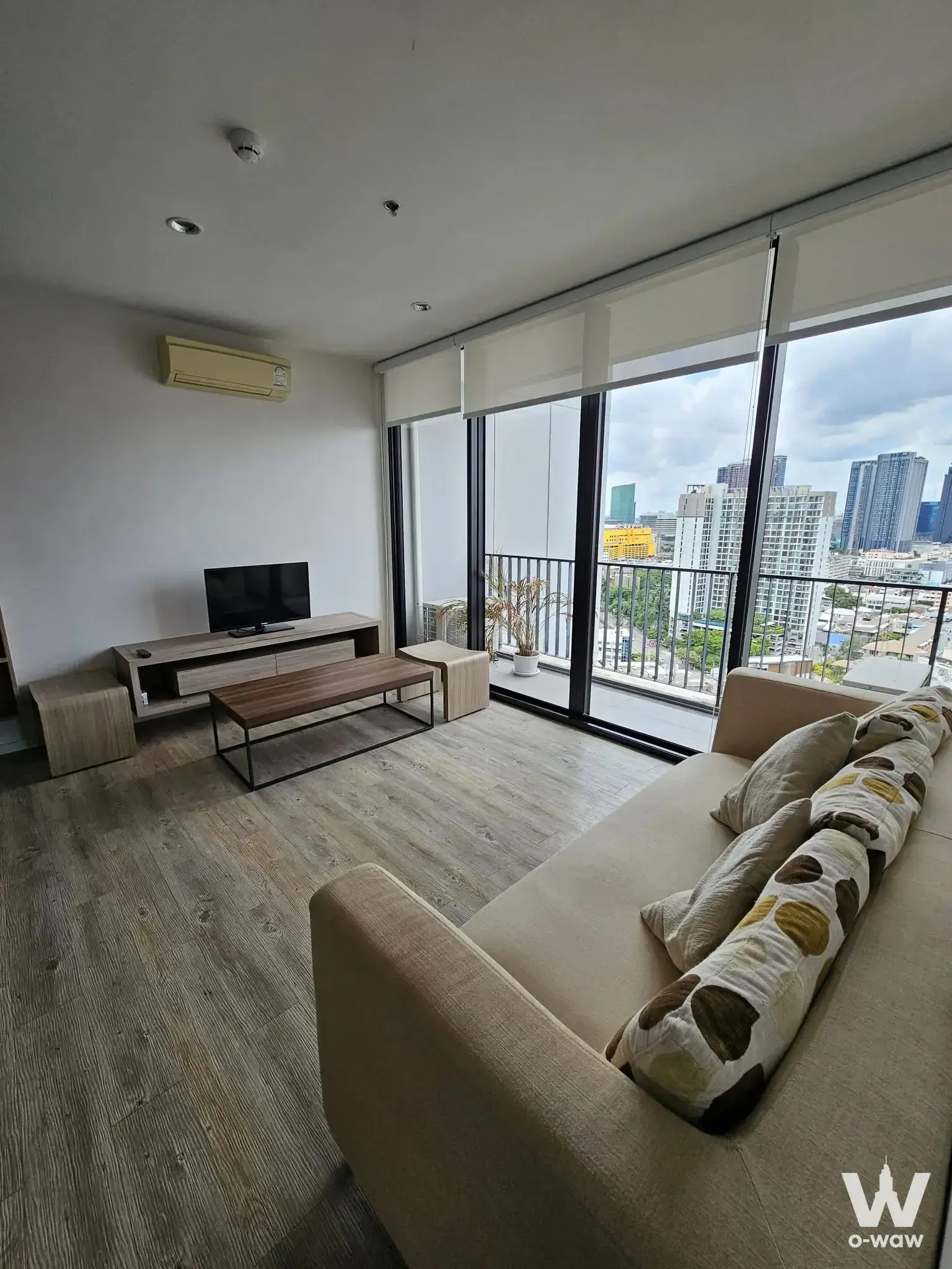 Living room in a 1-bed condo at The Issara Ladprao with beige sofa and city skyline view