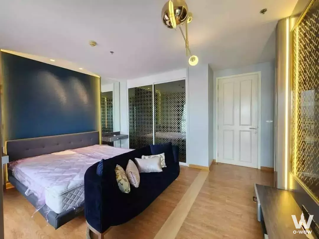 King bed with grey headboard against navy accent wall in 1-bed condo for rent at The Parkland Phetkasem