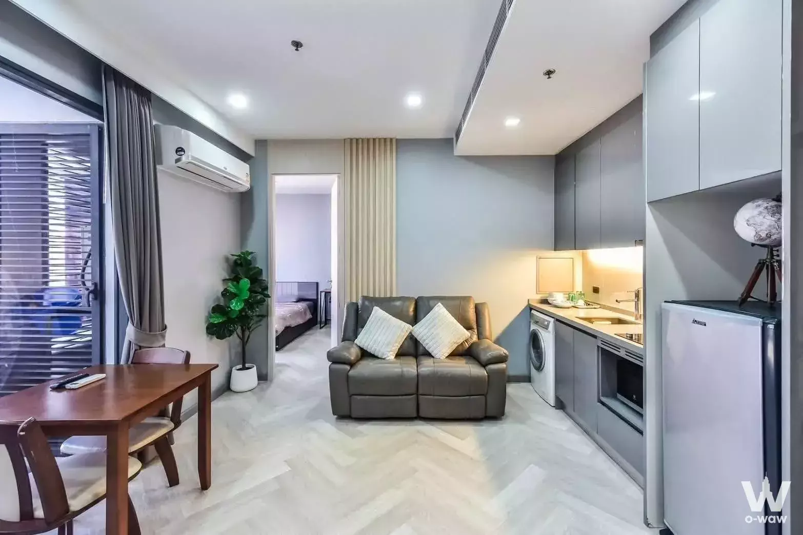 Modern 1-bed condo in Supalai River Place with herringbone floors, leather sofa, and open kitchen