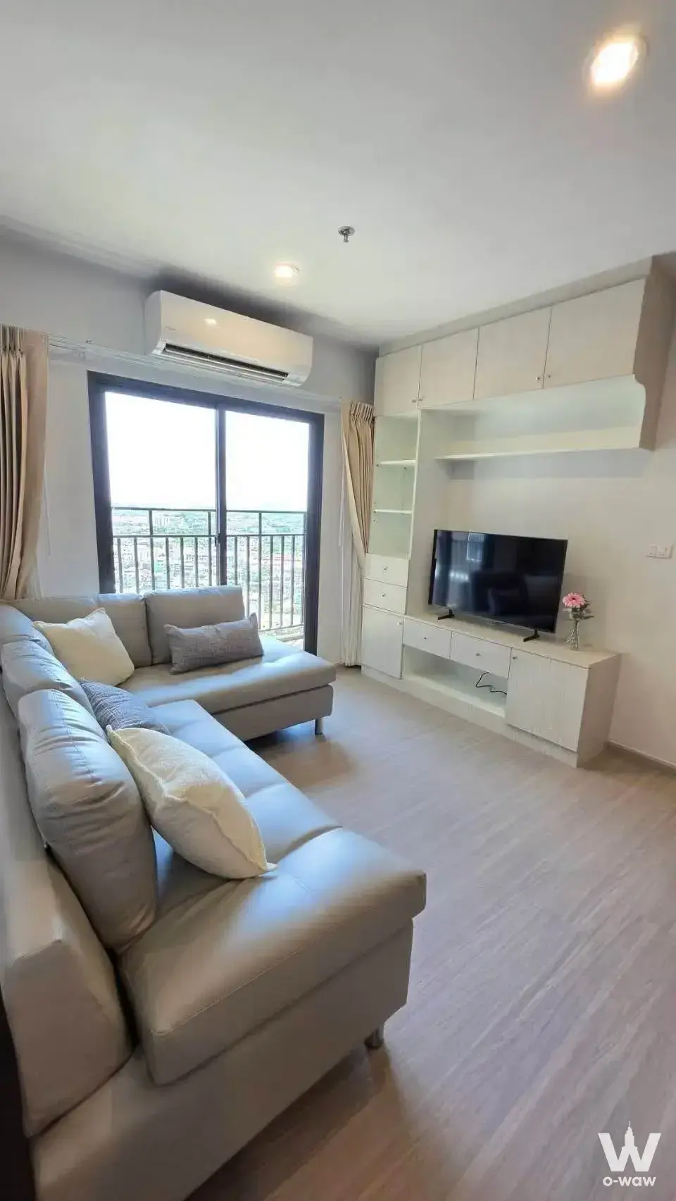 Modern living room with grey sectional sofa and city view balcony in 2-bed condo for rent at The Parkland Phetkasem 56