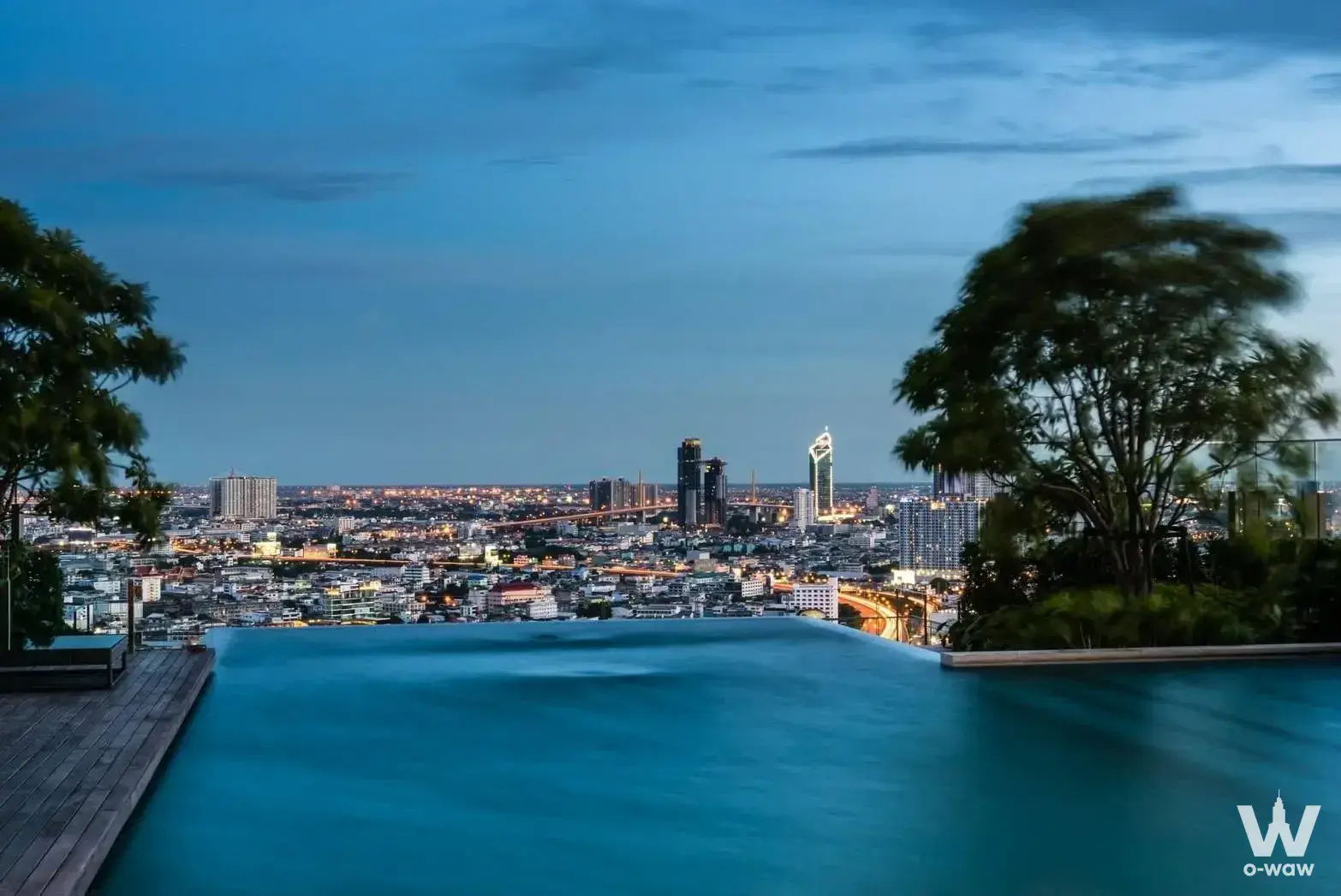 Rooftop infinity pool with city skyline views at dusk, part of a 1-bed condo for sale in The Bangkok Sathorn