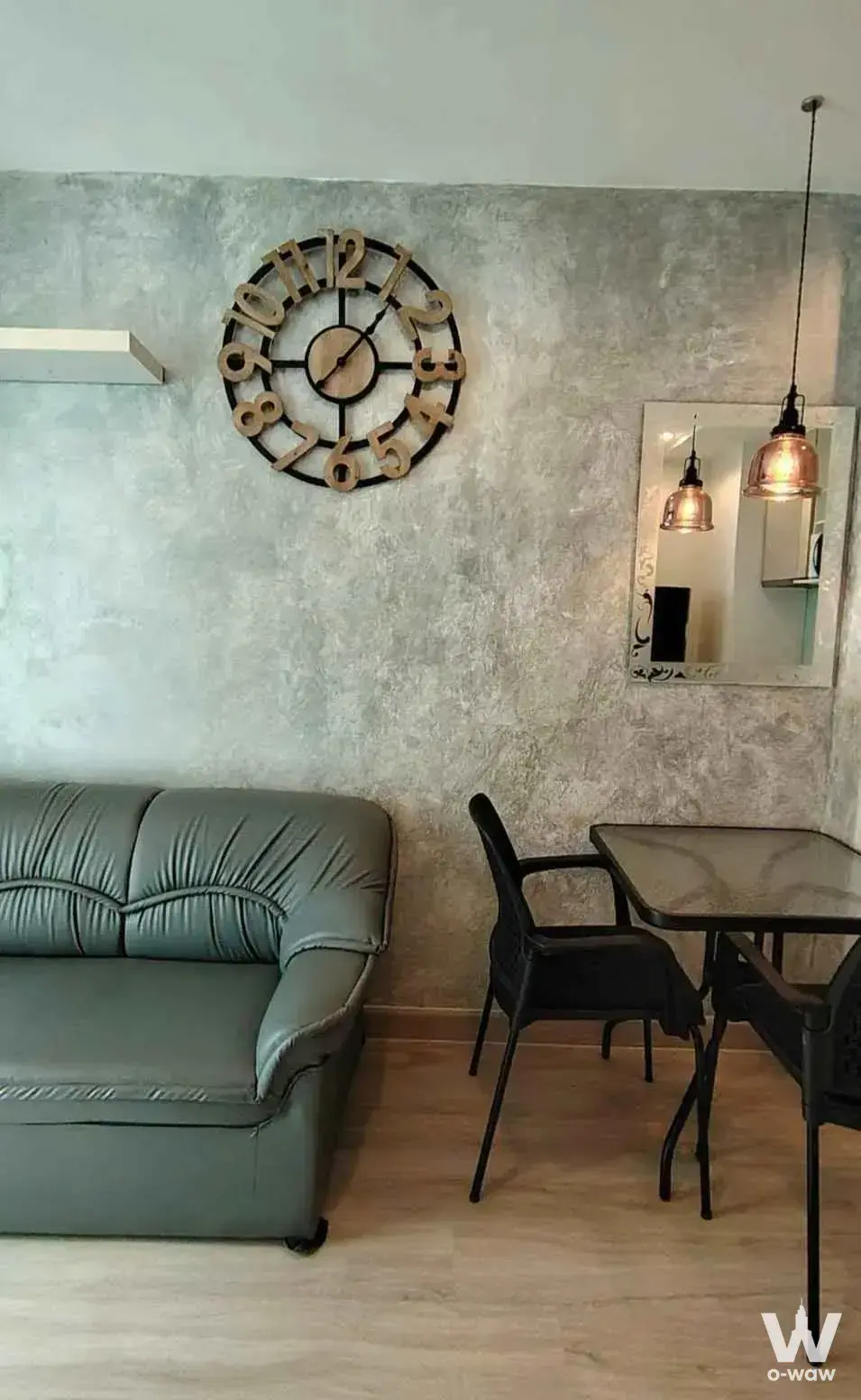 Industrial loft living space in a 1-bed Artemis Sukhumvit 77 rental with leather sofa and concrete wall