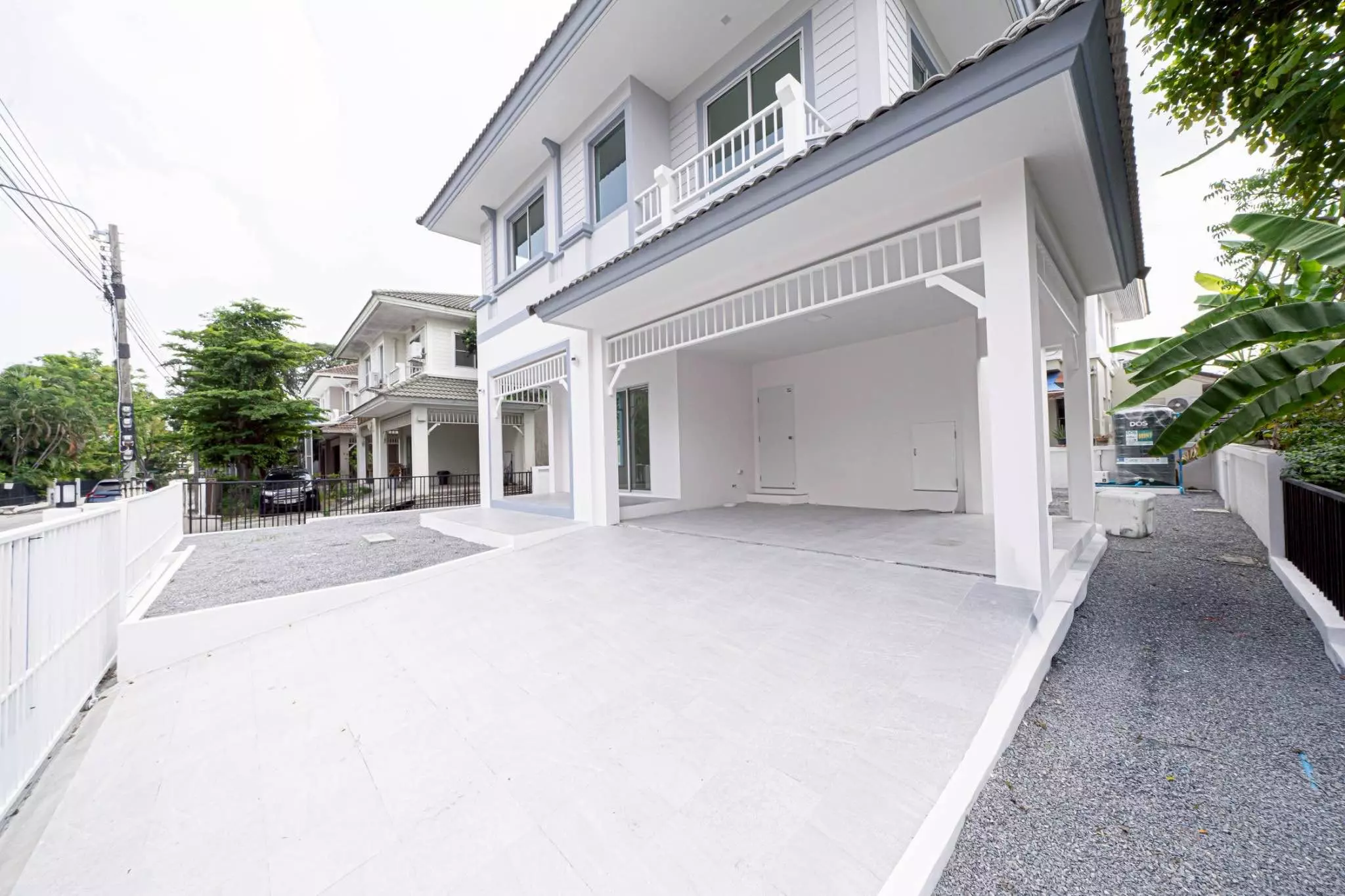 Modern 3-bed house for sale in Chonlada-Suvarnabhumi featuring white facade, grey trim, and spacious carport