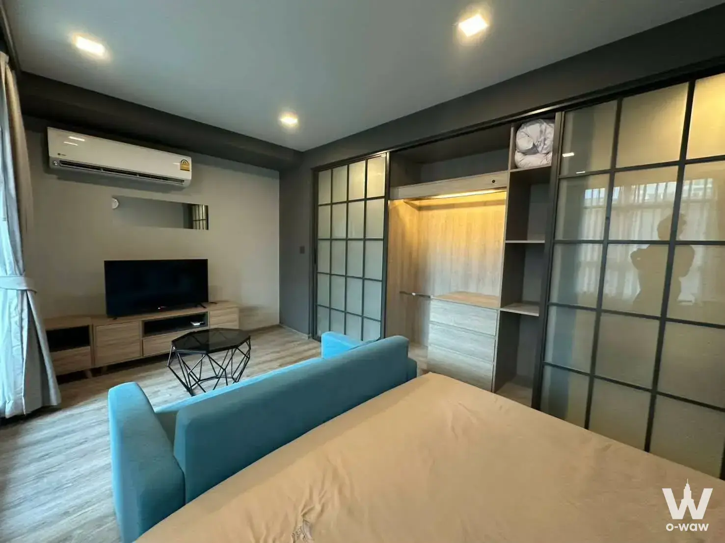Teal sofa and large bed with built-in wardrobe in this compact studio for rent at Maestro 19 Ratchada