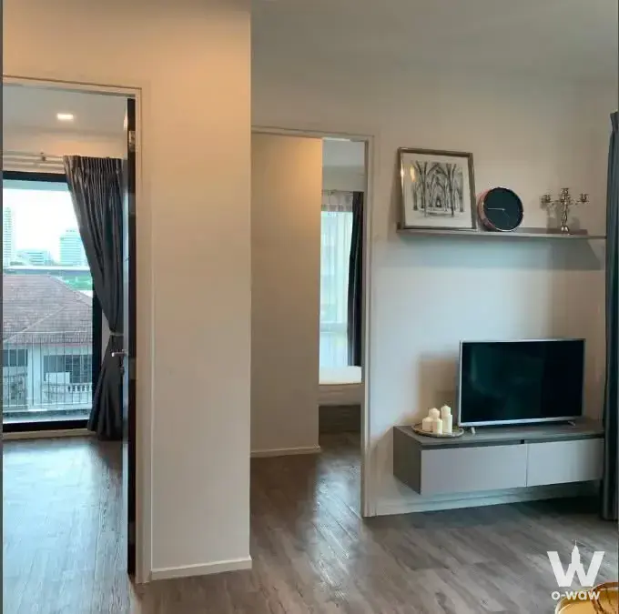 Modern living room in a 2-bed condo for rent at Brown Condo Ratchada 32, featuring grey laminate flooring and city views