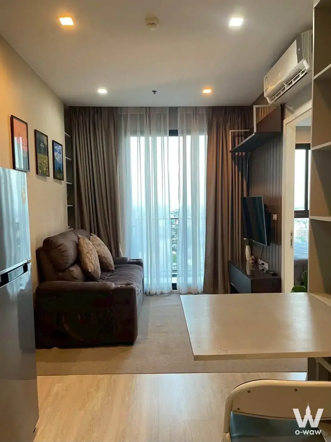 Modern 1-bed condo living room at Quinn Condo with wood floors, sofa, TV wall, and balcony city views