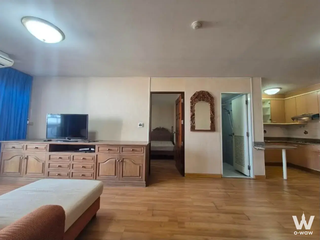 Furnished living room with TV console and blue curtains in 2-bed condo for sale at Floraville Serviced Apartment Bangkok
