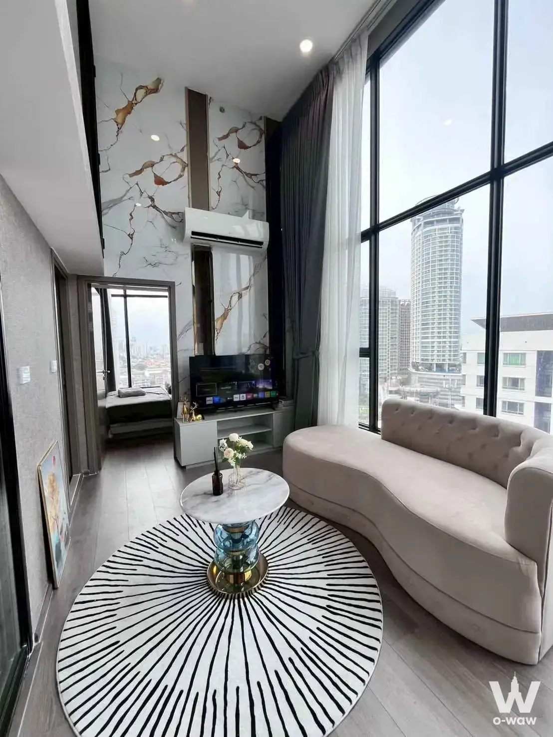 Modern condo living room with floor-to-ceiling windows, marble accent wall, and city skyline view in KnightsBridge Space
