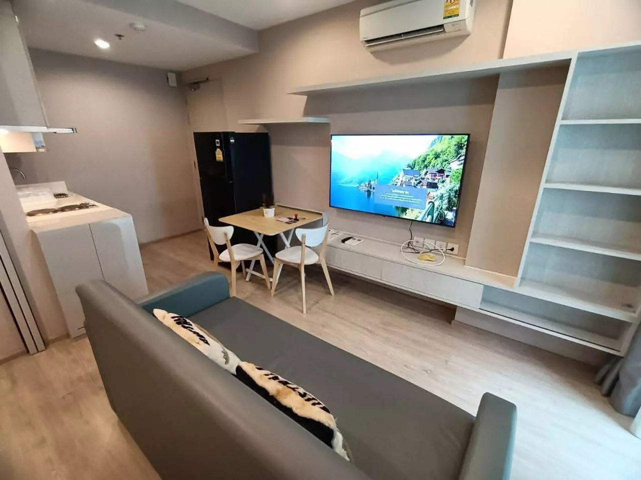 Modern living area in 1-bed condo for sale at Ideo Q Chula-Samyan with grey sofa, TV unit, and open kitchenette