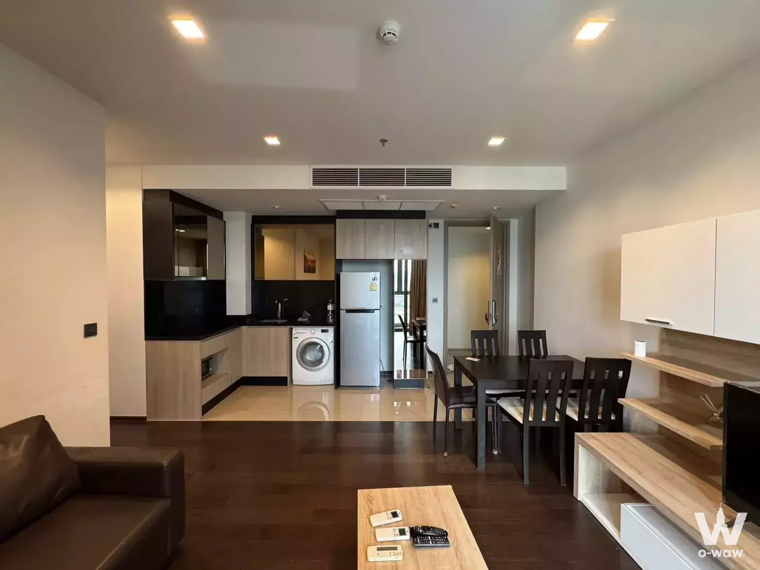 Modern open-plan living and dining area in 2-bed condo for rent at THE LINE Ratchathewi with dark wood floors and balcony