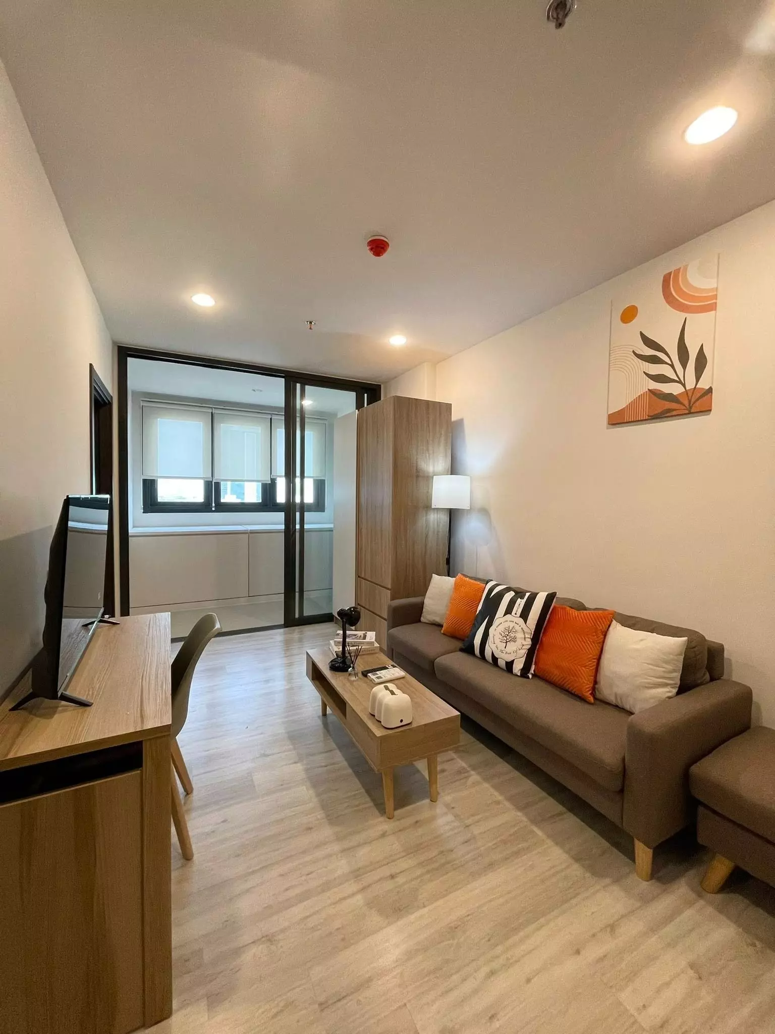 Modern 1-bed condo living room in XT Huai Khwang with brown sofa, wood floors, and balcony access