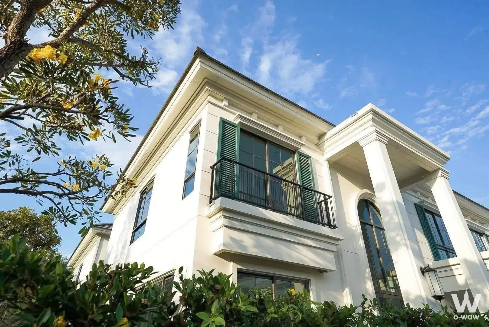 PYNE by Sansiri 0-bed condo exterior with white stucco, green shutters, and classical columns