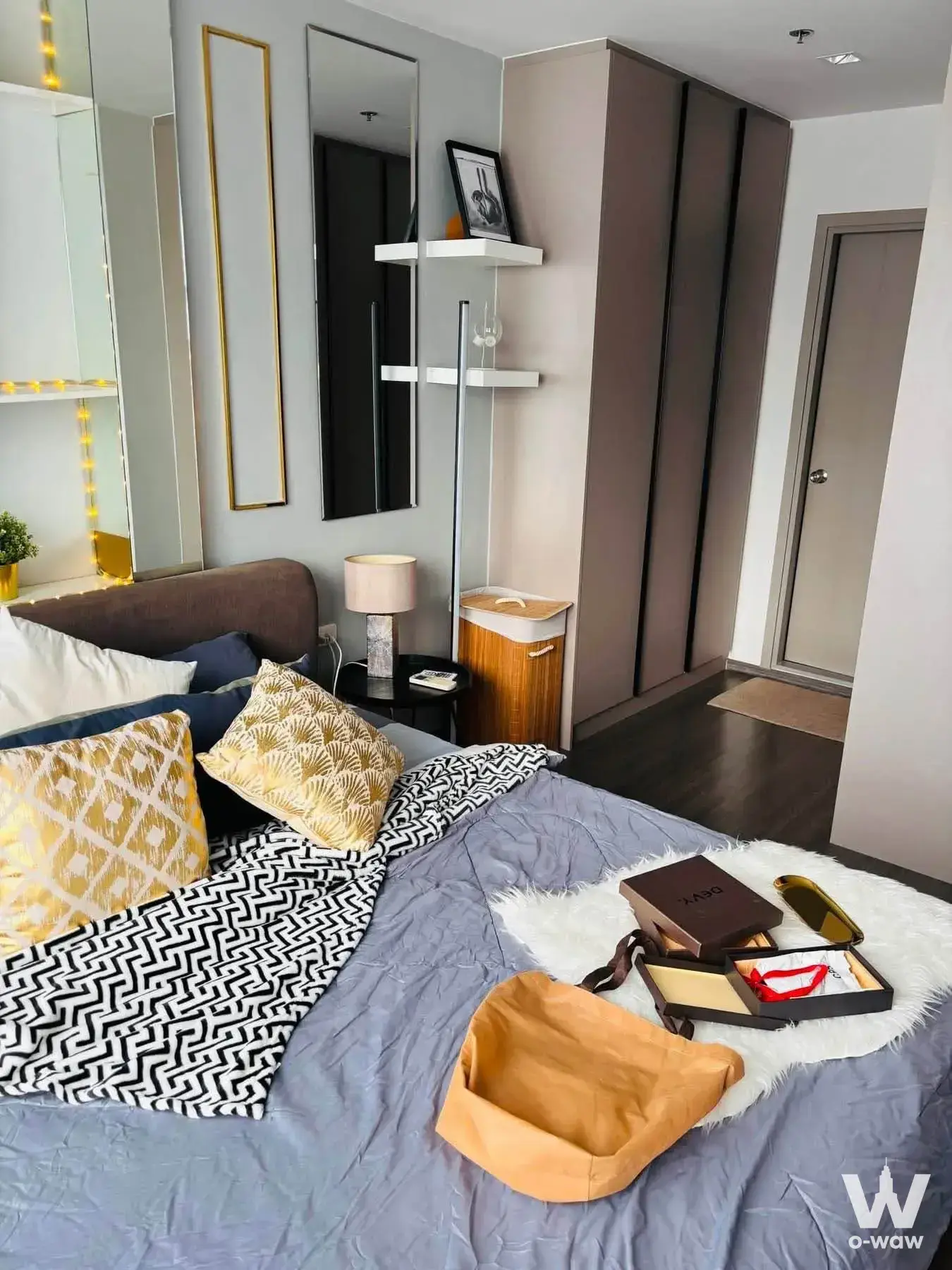 Modern bedroom in 1-bed Ideo Sukhumvit 93 condo with queen bed, gold mirrors, and taupe wardrobe