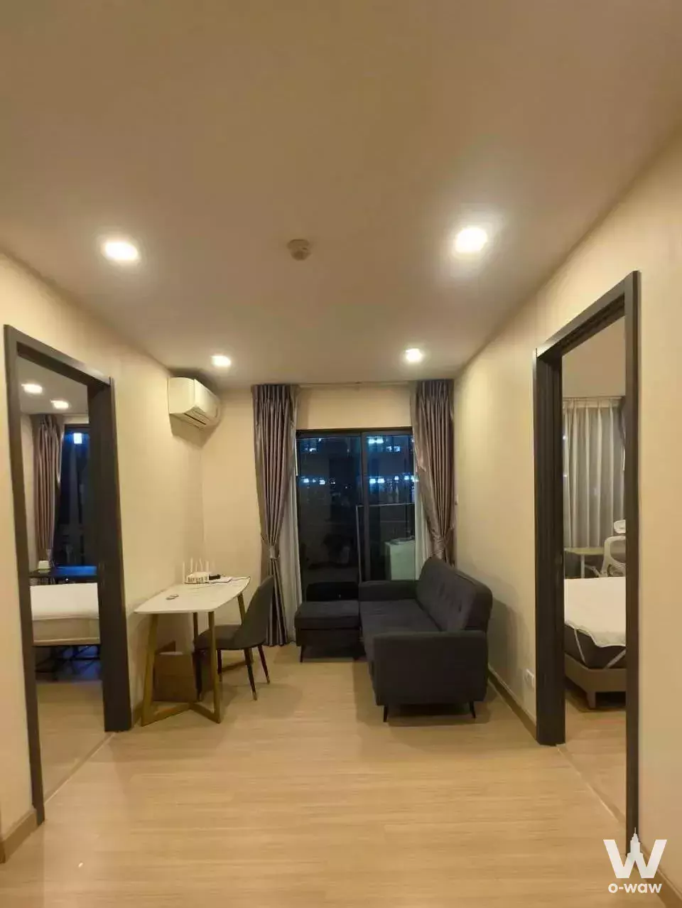 Modern living room with L-shaped sofa and balcony view in 2-bed condo for rent at Supalai Prime Rama 9