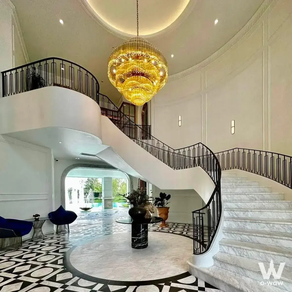 Grand double-height foyer with curved marble staircase, crystal chandelier, and view to pool at 0-bed house for sale in