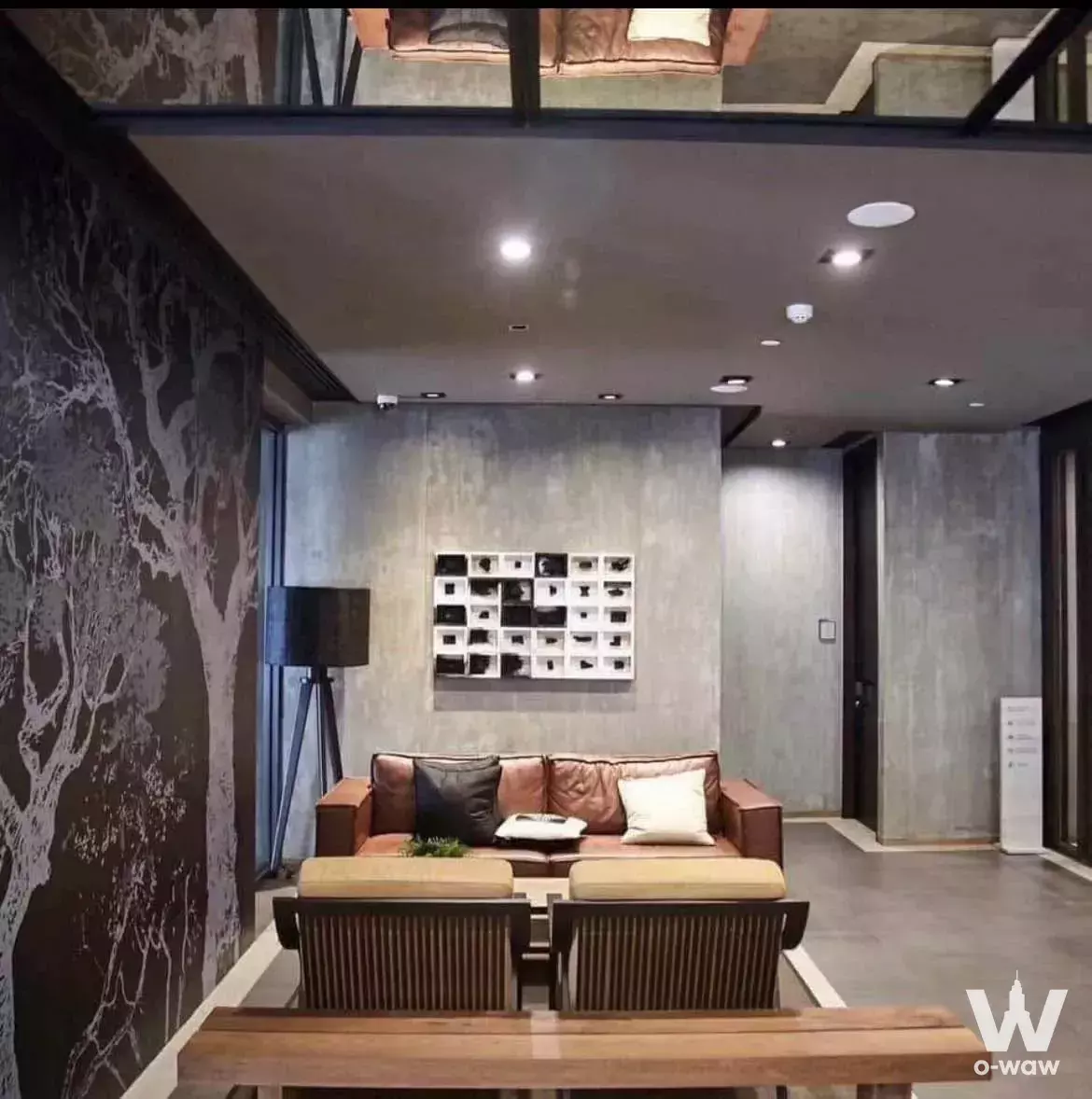 Modern industrial living room with high ceilings, mezzanine, and leather sofa in 1-bed condo for rent at Centric Ari Station