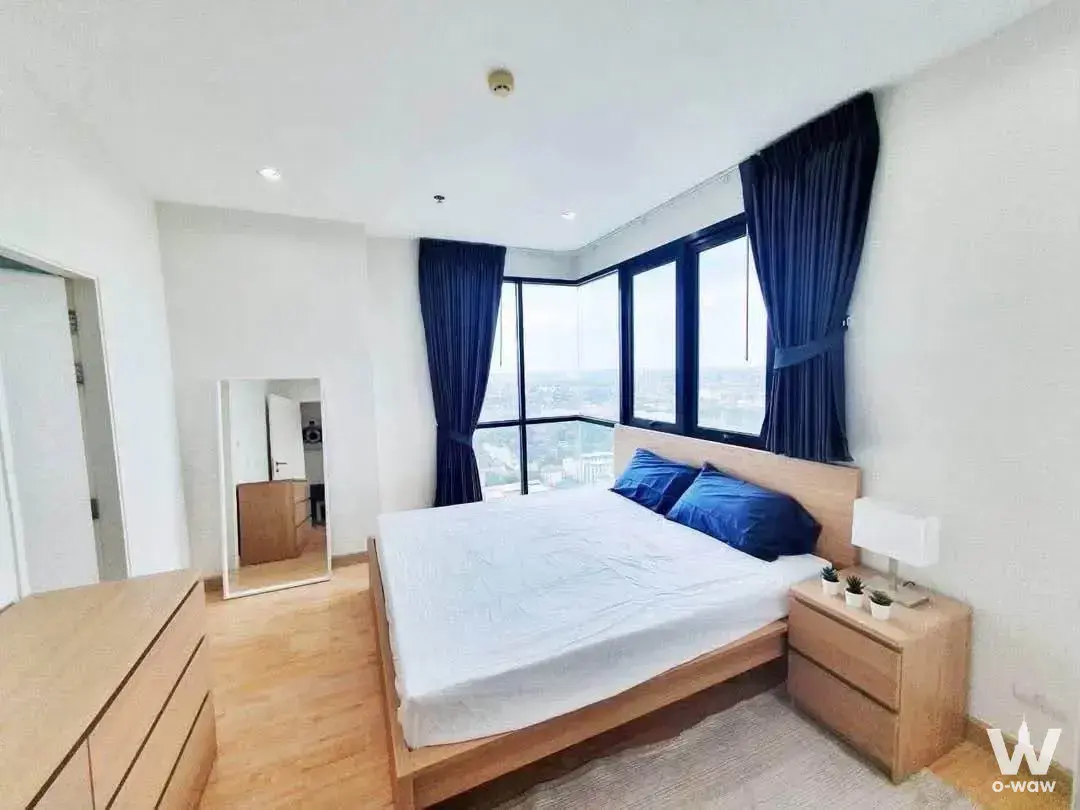 Master bedroom in Astro Condominium with light wood platform bed and bay window city views