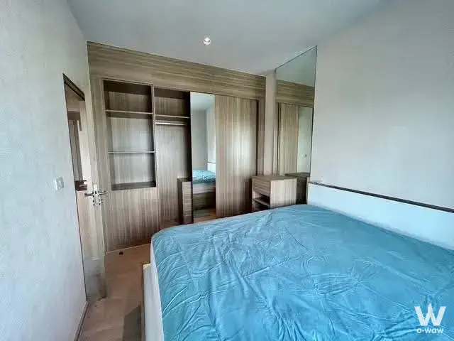 Modern bedroom in Altitude Unicorn condo with blue linens, mirrored wardrobe, and wood-effect flooring