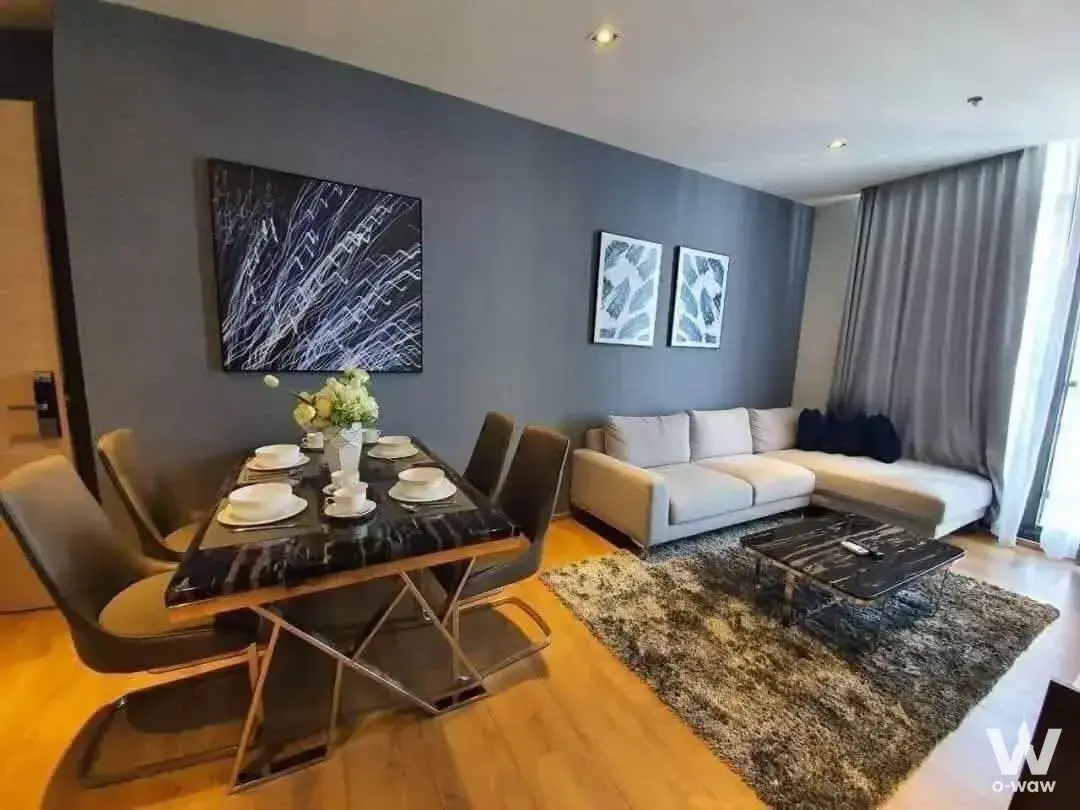 Open-plan living and dining area in a Park24 2-bed condo for sale, featuring charcoal grey walls and marble accents