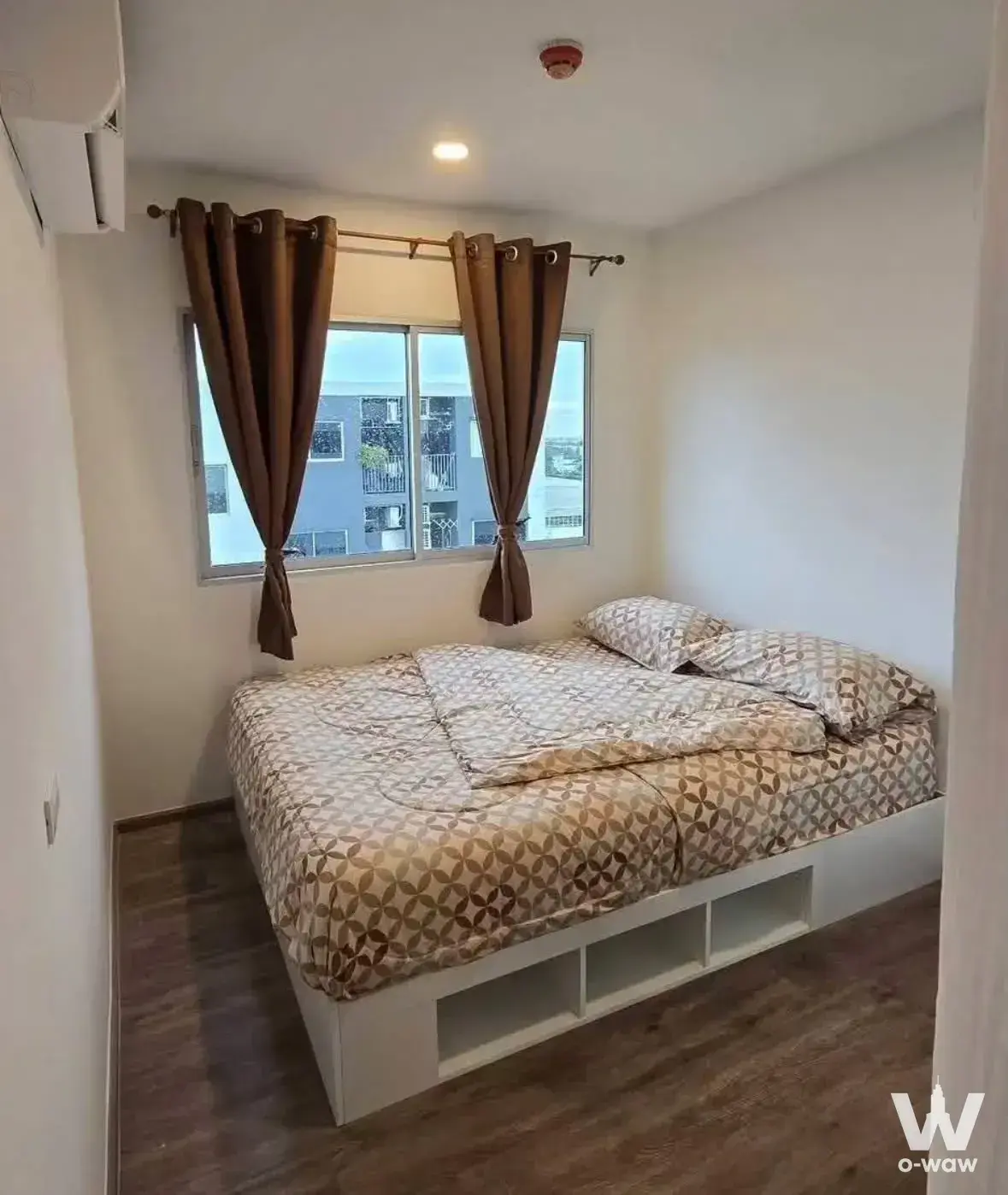 Compact bedroom in Sena Kith Srinakarin condo featuring a queen bed with built-in storage cubbies