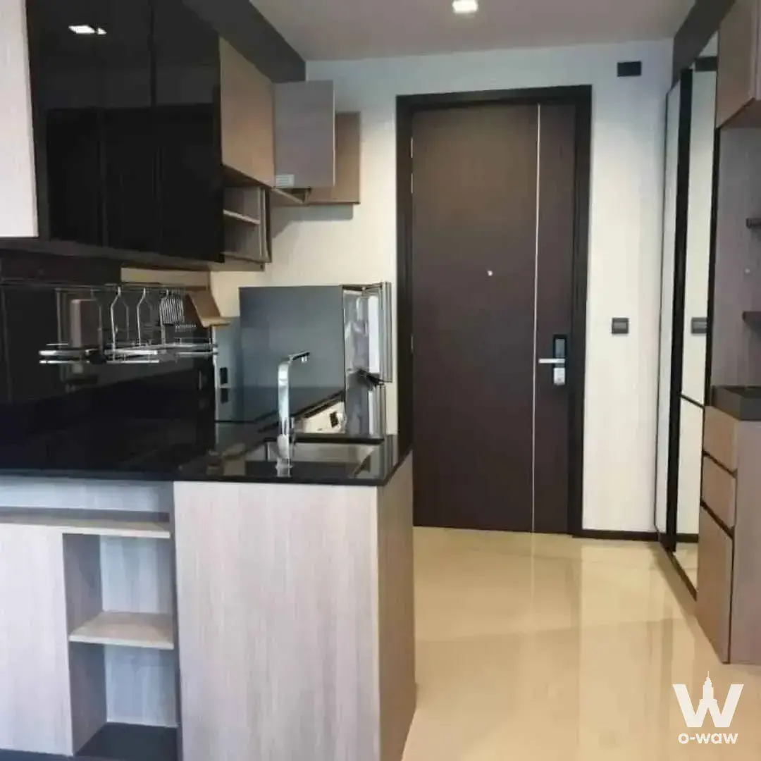 Modern kitchen in THE LINE Asoke-Ratchada condo with black glass cabinets and dark granite counter