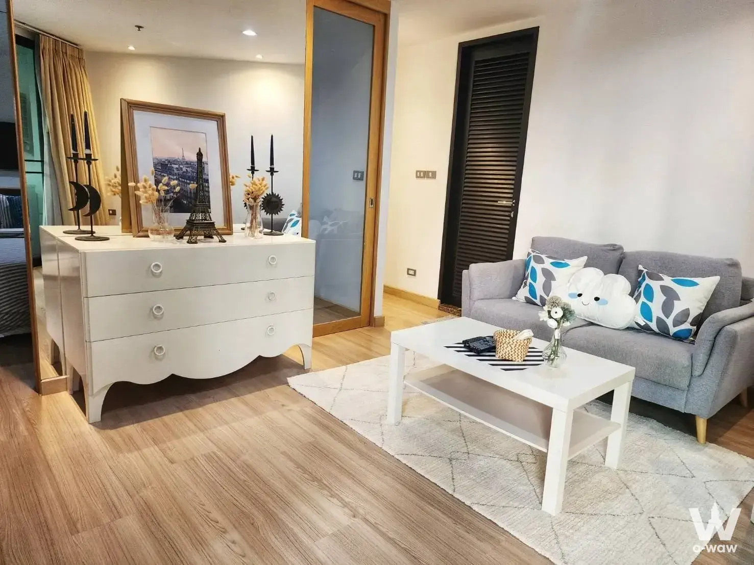 Bright living room with grey sofa and wood floors in 1-bed townhouse for sale in 59 Heritage Bangkok