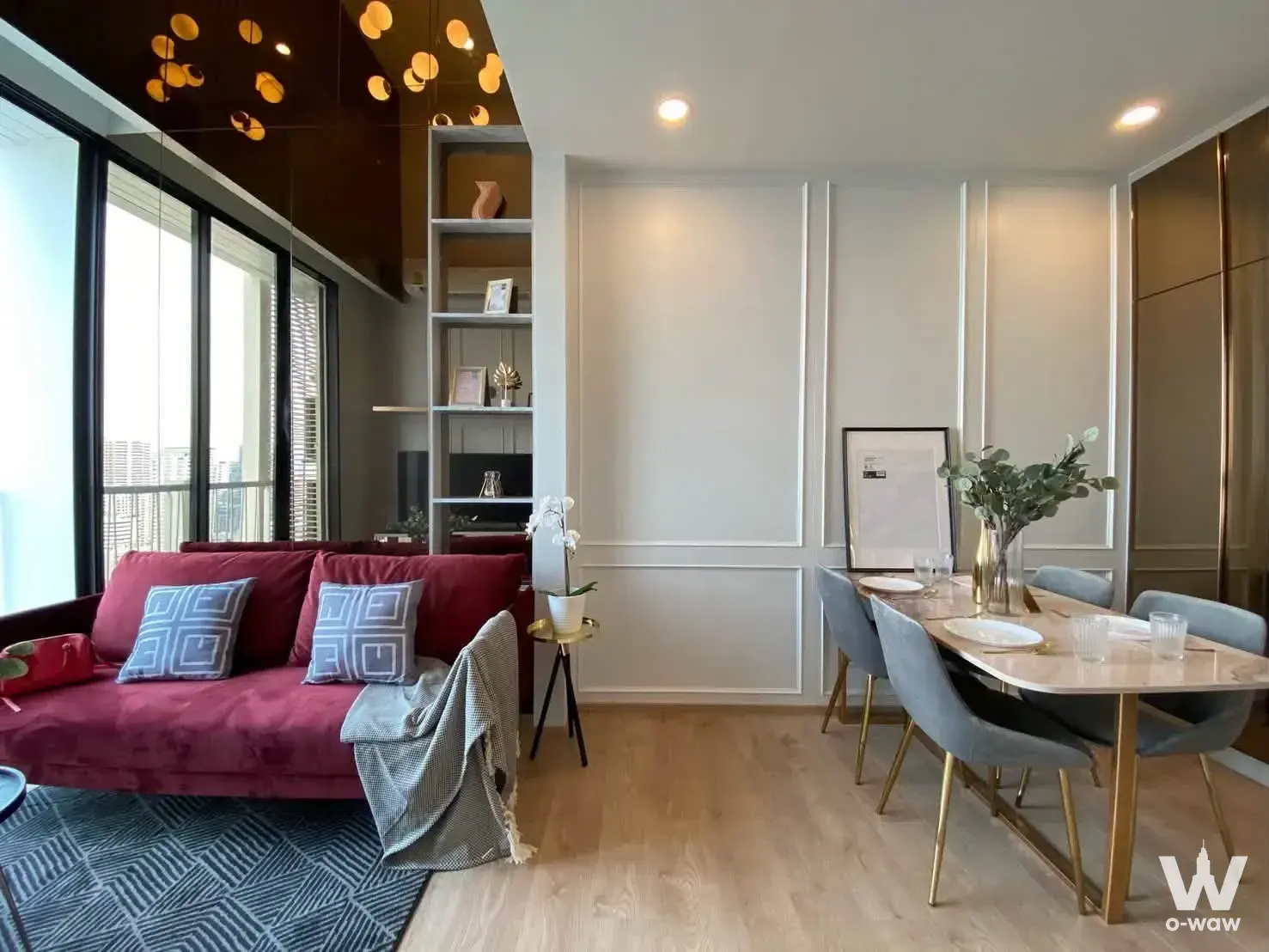 Modern living room with red velvet sofa and marble dining table in 2-bed condo for rent at Noble Recole Bangkok