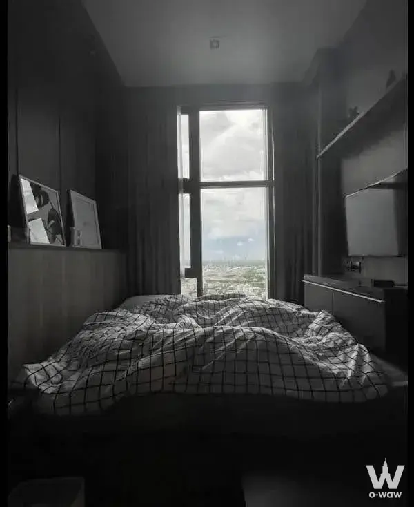Modern 1-bed condo bedroom in THE LINE Sukhumvit 71 with dark wood walls and city skyline view