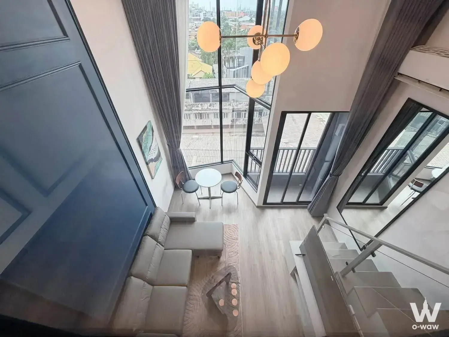 Modern duplex living room in KnightsBridge Space condo with grey sofa, dining nook, and city views