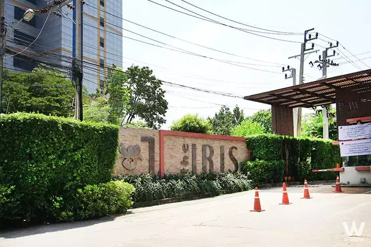 Gated entrance of The Iris Condo with manicured hedges and security booth for 1-bed rental