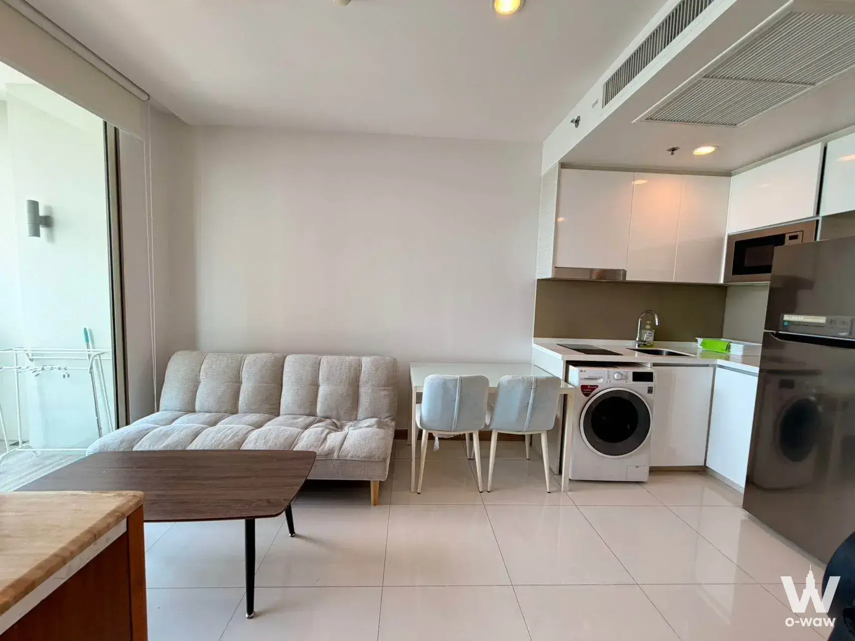 This 1-bed condo at The Riviera Wongamat Beach has an open-plan living area, grey sofa and full kitchen