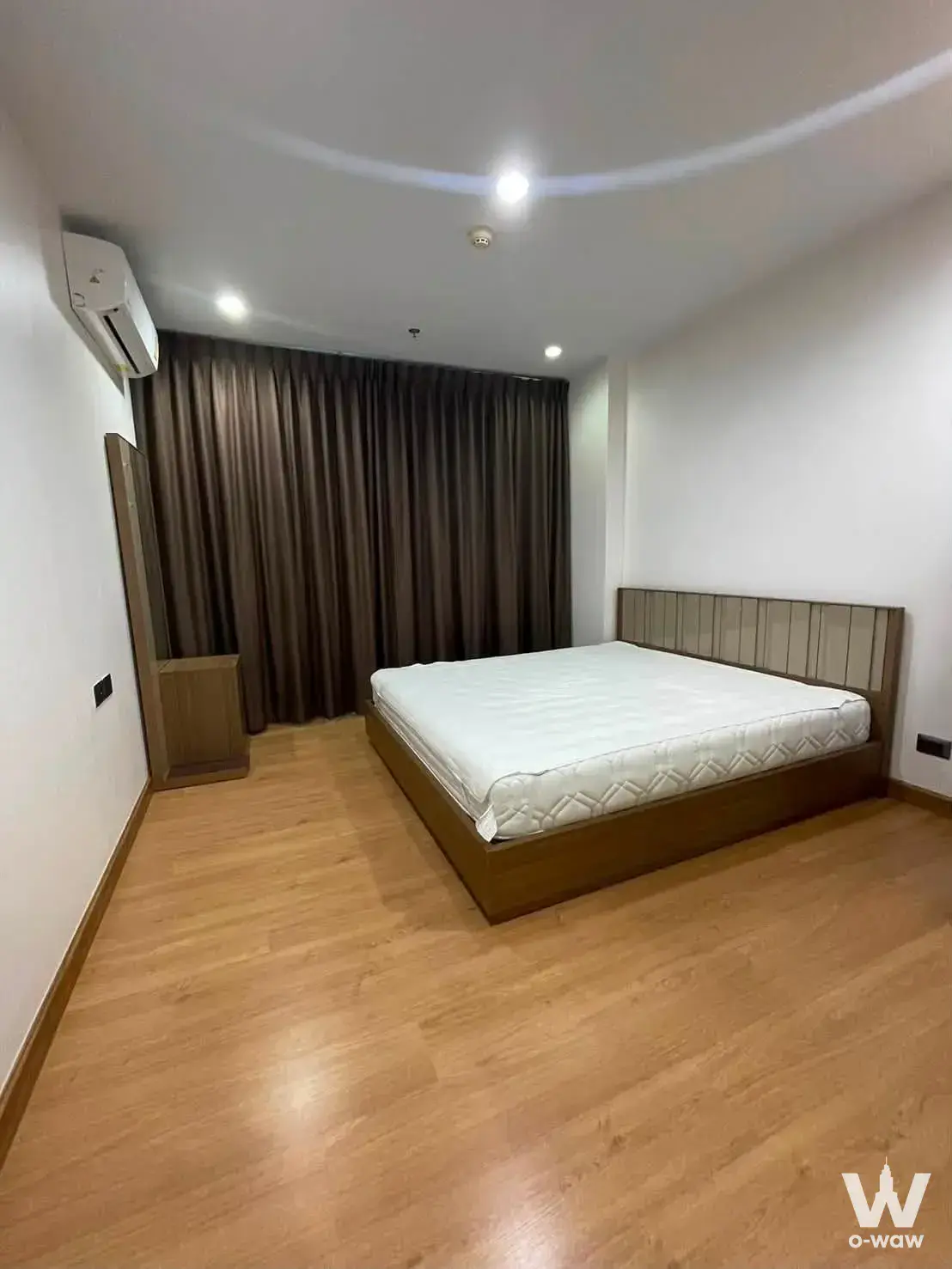 Queen bed with slat headboard in a 1-bed condo for rent at Supalai Wellington II