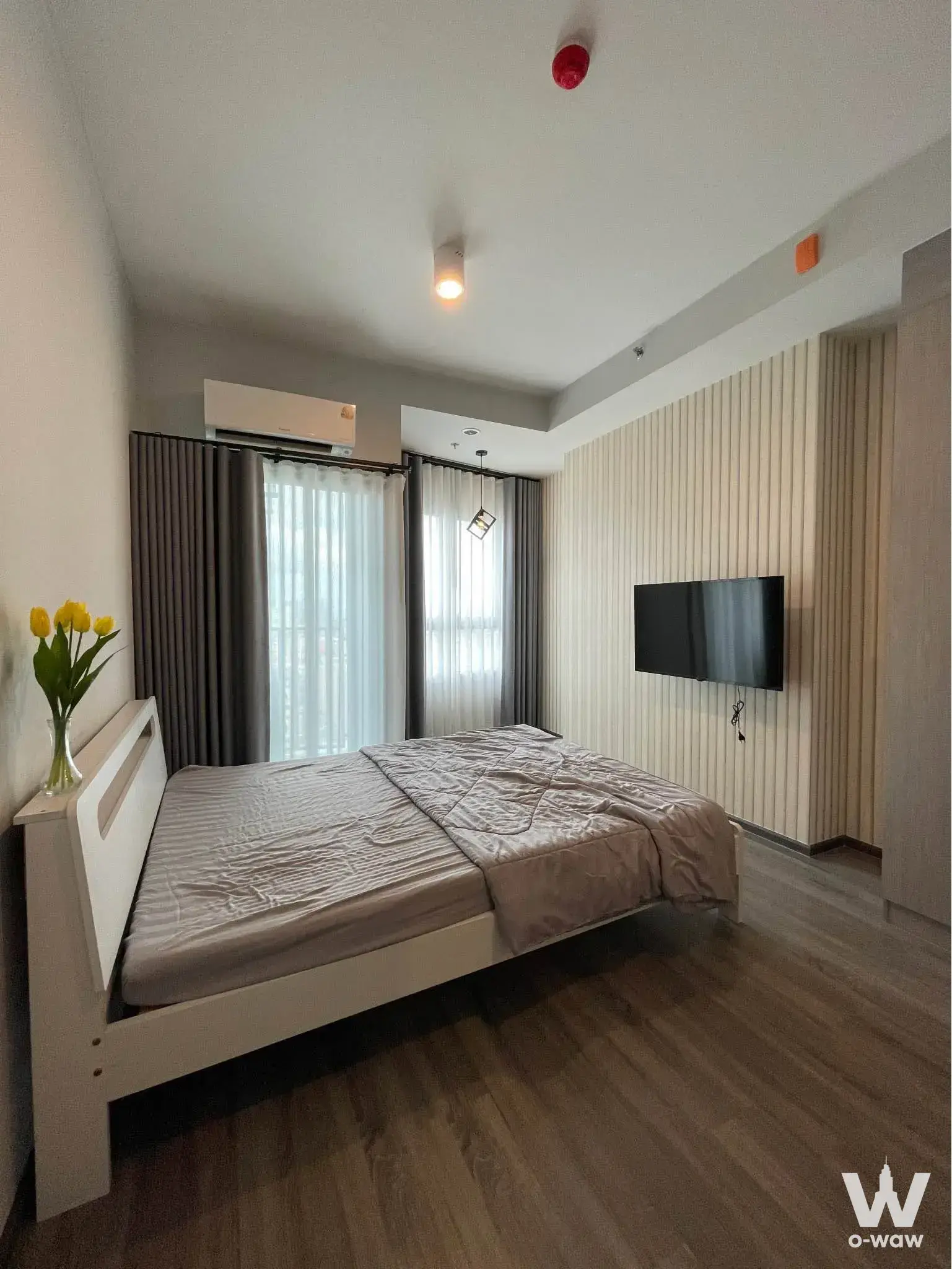 Modern bedroom in 1-bed condo for rent at Ideo Ramkhamhaeng Lamsali Station with white bed and wood slat wall