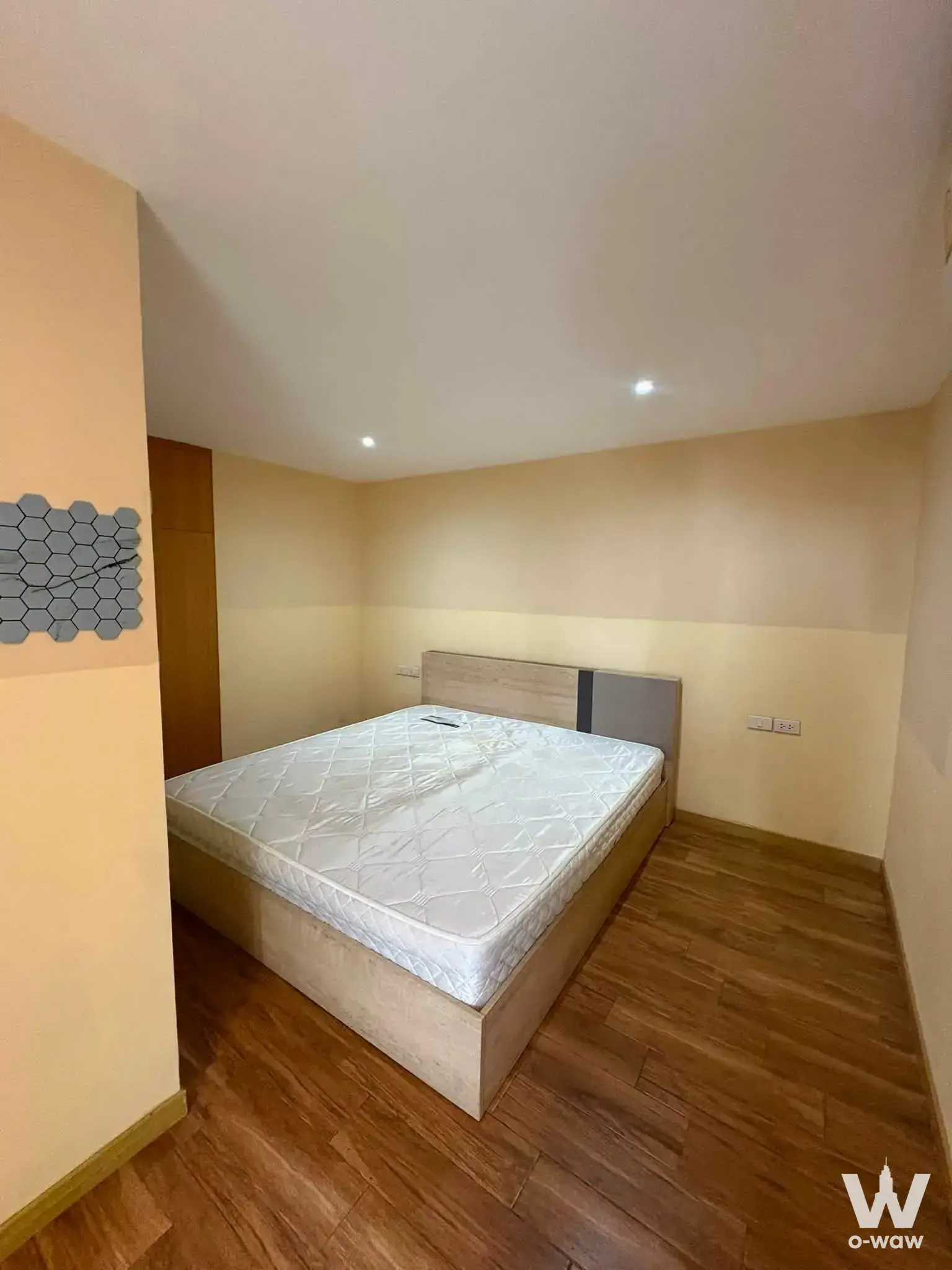 Modern 1-bed condo bedroom in Pentafield City Residence with light oak headboard and hexagonal tile accent