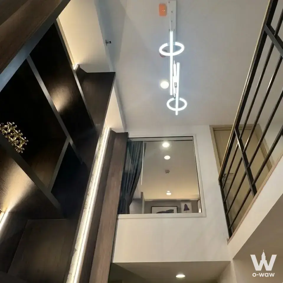 Modern mezzanine with dark wood shelves, LED lighting, and sleek black railing in 2-bed Culture Chula rental