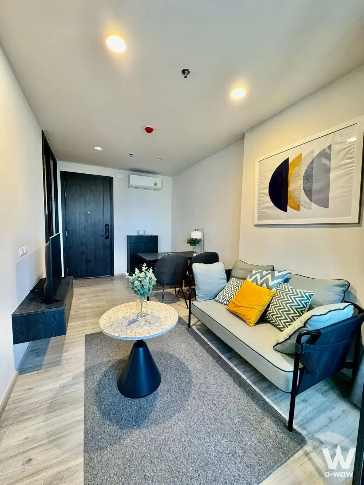 Modern living room in 1-bed condo for rent in XT Huai Khwang with beige sofa, grey rug, and light wood flooring
