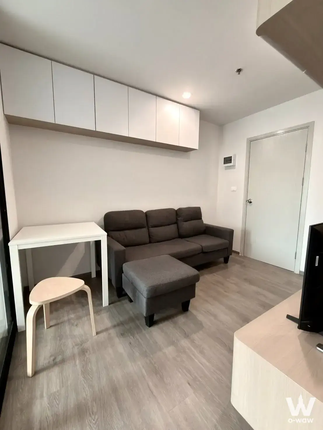 Living room in Regent Home Wutthakat 1-bed condo with dark-grey sofa and floating white cabinets