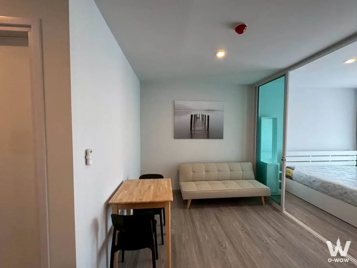 Studio living area with beige futon and glass partition in Regent Home Bangna rental unit