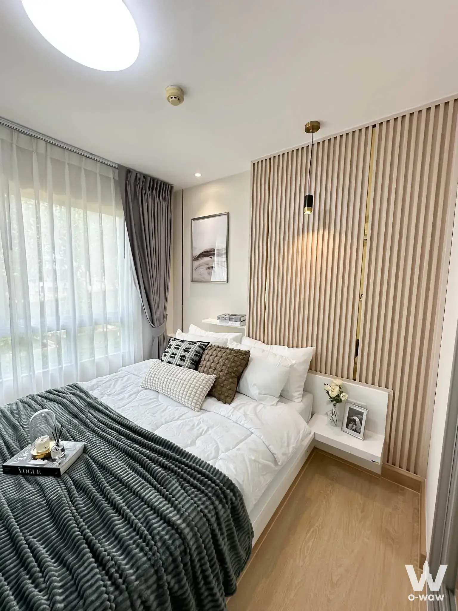 Bright bedroom in 1-bed condo for sale at The Trust Residence Pinklao with light wood floors and modern slat headboard