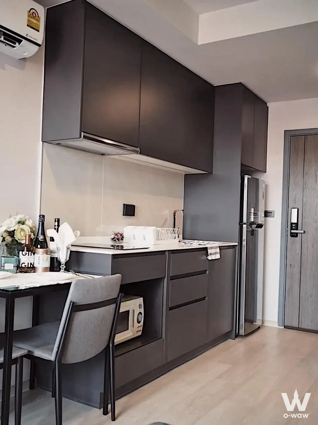 Venio Sukhumvit 10 kitchen with charcoal cabinetry, quartz counters, and dining table for two