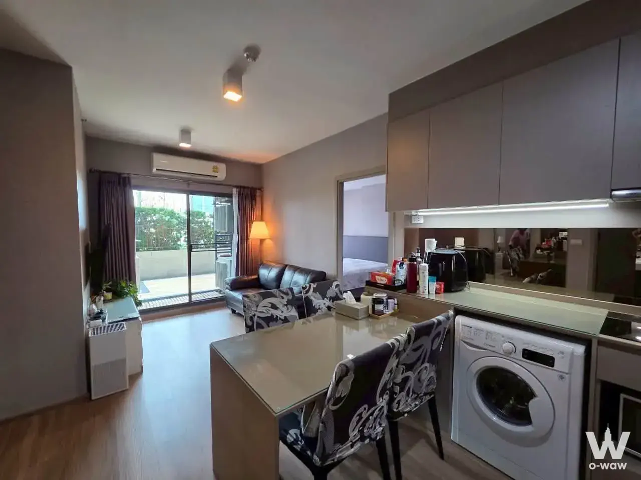 Ideo Sukhumvit 93 two-bedroom condo with light wood floors, grey walls, and a modern kitchen featuring taupe cabinets