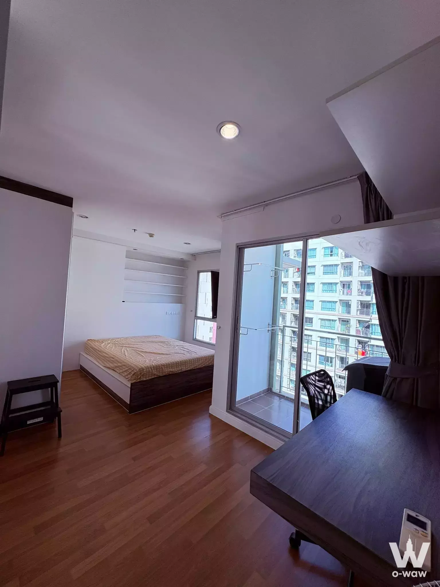 Bedroom in Lumpini Park Riverside condo with wood floors, built-in shelves, desk, and balcony view