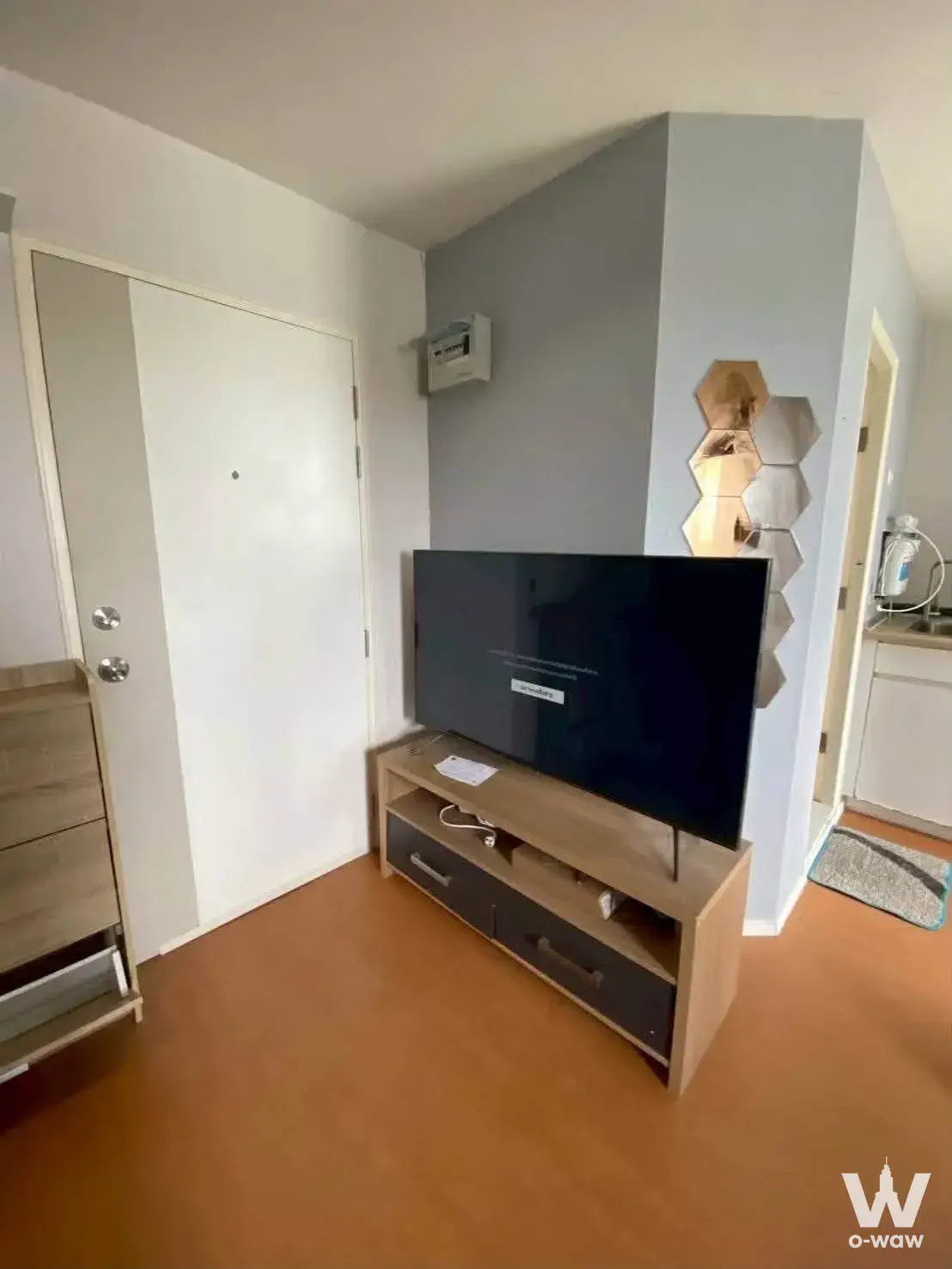 Living room in Lumpini Mega City Bang Na condo with grey accent wall and hexagonal mirror cluster