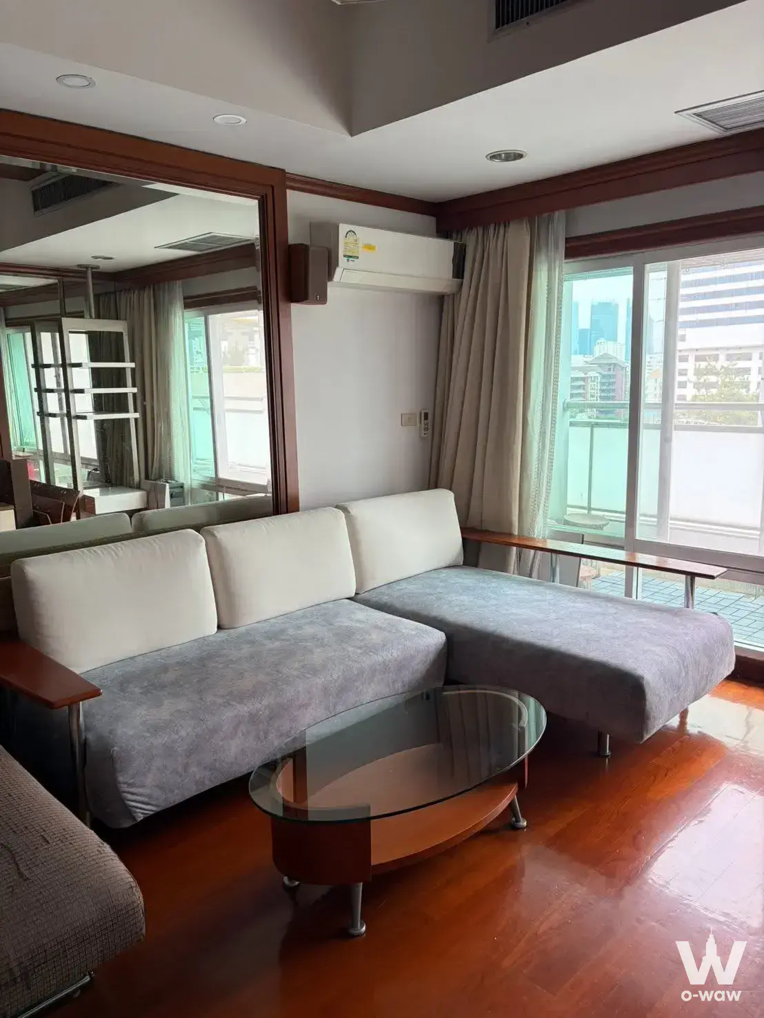 L-shaped grey sofa and glass coffee table in a high-floor 3-bed condo for sale at Baan Nonzee Condominium