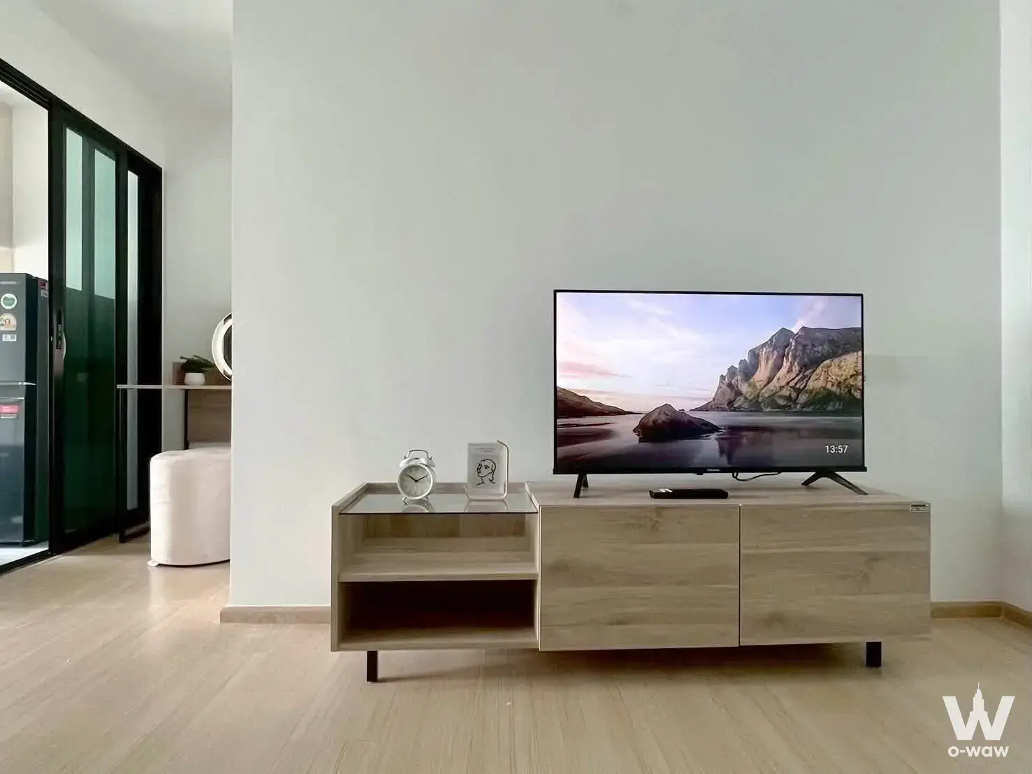 Modern condo living room with light oak flooring, white walls, and a low-profile TV console