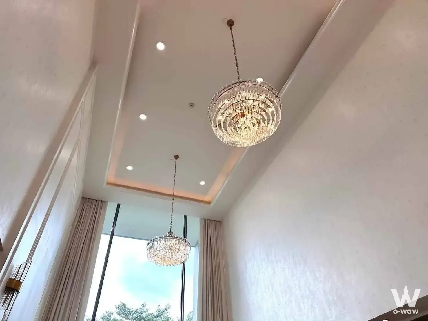 Double-height ceiling with crystal chandeliers and floor-to-ceiling windows in a Sukhothai Residences unit