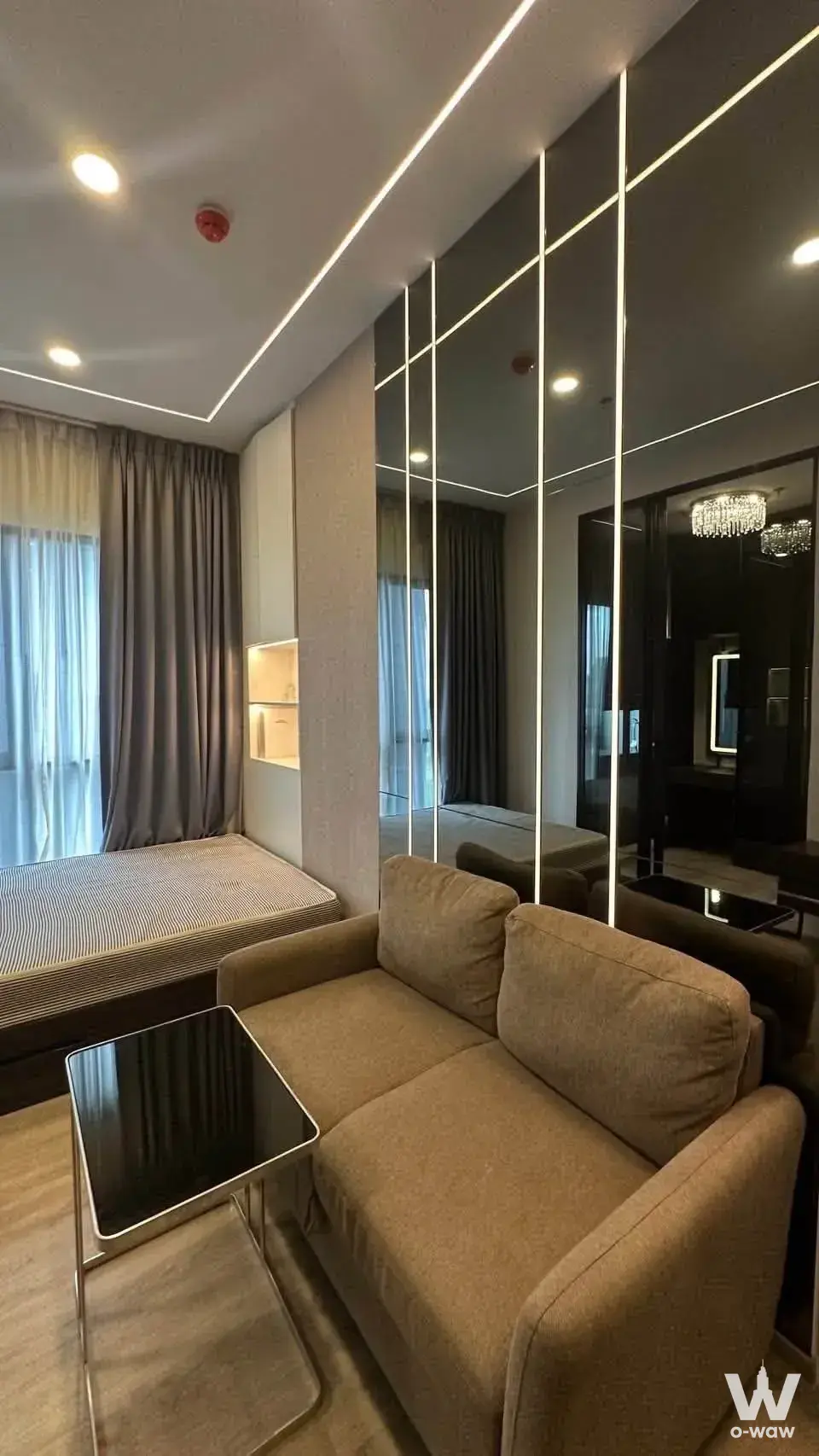 Modern studio with mirrored walls, LED lighting, and a built-in bed platform